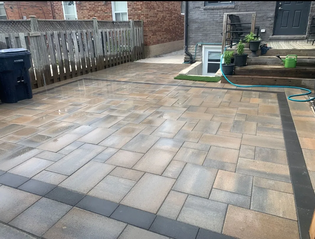 Newly installed backyard interlock patio with contrasting border