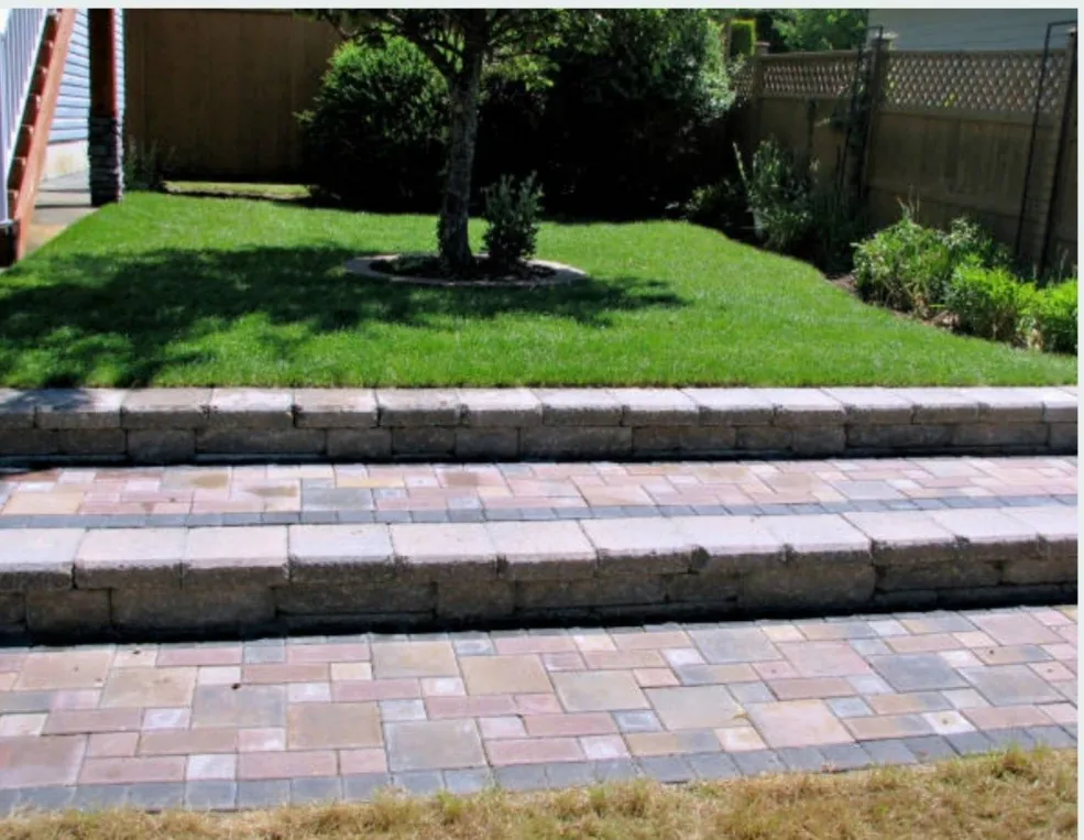 Interlocking paver steps leading to a freshly sodded backyard lawn